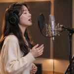 방음 스튜디오에서 마이크를 마주하고 녹음에 집중하는 가수의 모습